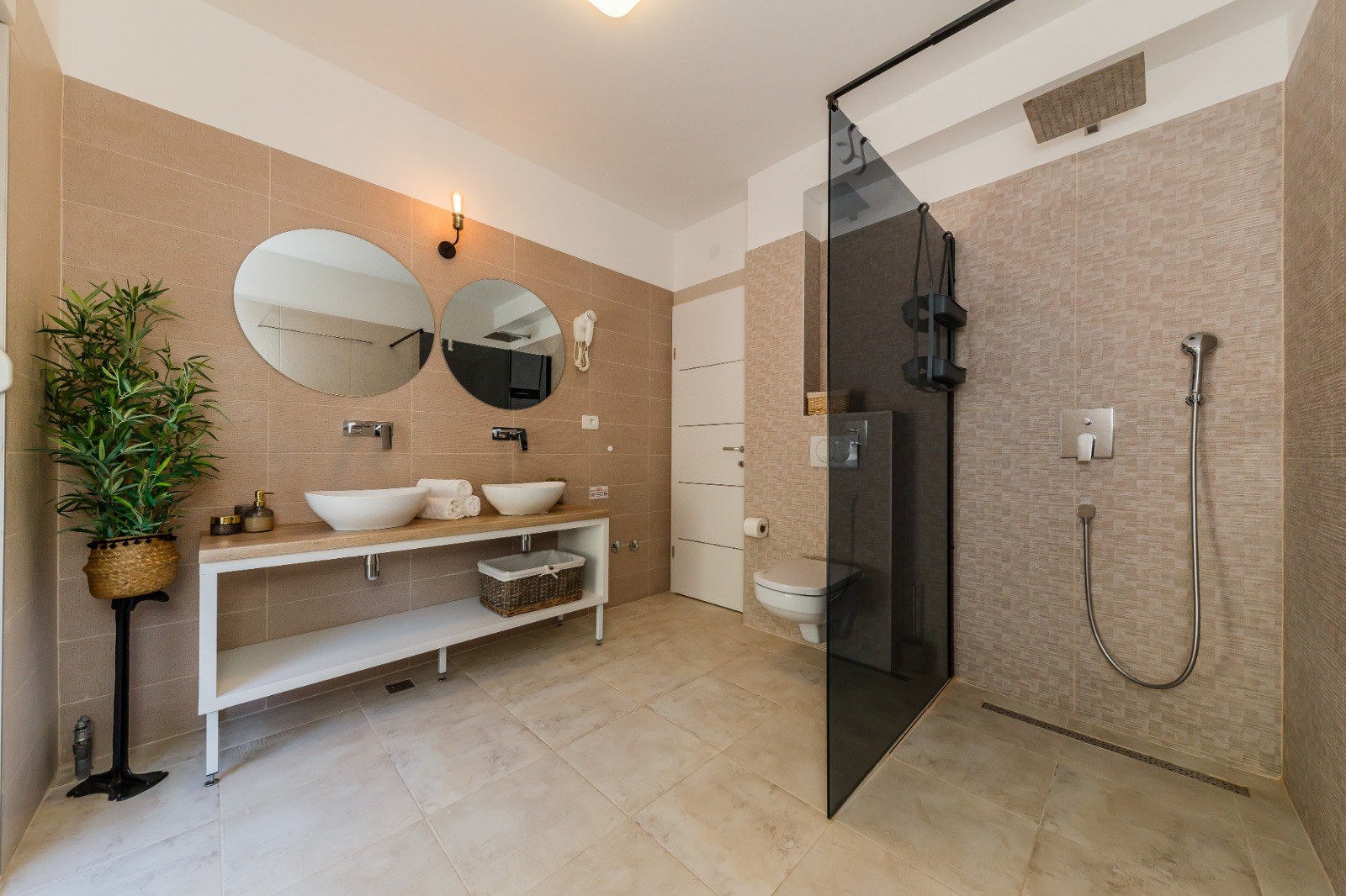 Bathroom with two basins, round mirrors and a glass walk-in shower